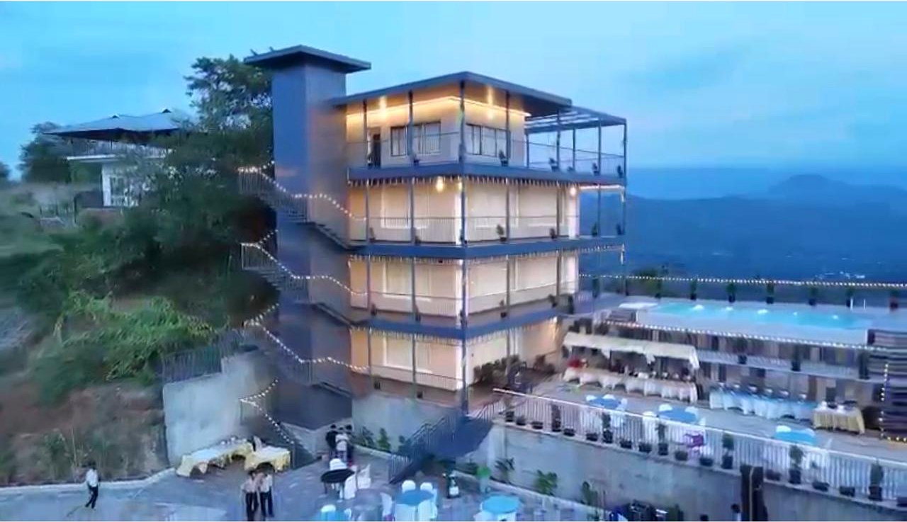 RPEES Mountara at dusk, lit from within, with the pool and the Attappadi valley beyond